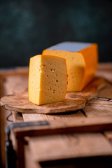 Medium hard cheese gouda edam on wooden board on sunlight table traditional table texture