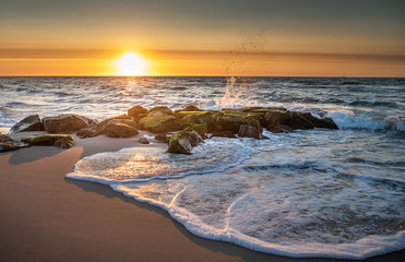 Sunrise over the Atlantic seashore with a stone jetty in the foreground