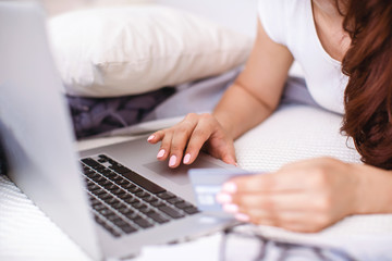 Fototapeta premium Self-isolation at home. woman hands shopping online at home with bank card and laptop.