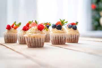 Fresh, delicious cupcakes with yogurt cream and fresh berries. Blur background.