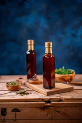 Two bottles of olive oil with bowl of olives and salad on wooden board