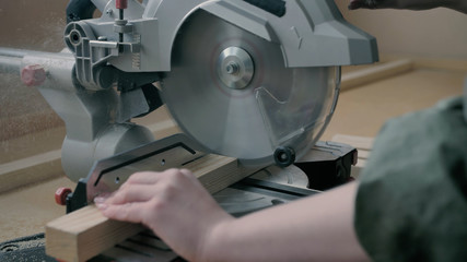Girl in a workshop sawing wooden materials