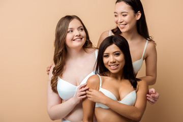 smiling plus size multicultural women in bras isolated on beige