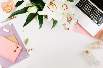 Creative colorful female workspace with laptop computer, flowers, colorgul notebooks, golden clips on white desk. Flat lay, top view