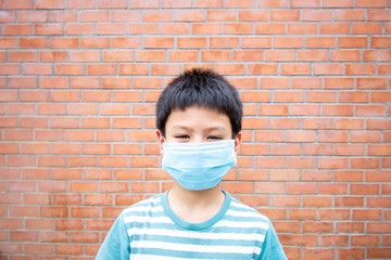 Asian boy wearing a mask background brick wall.