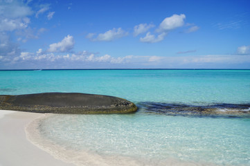 Stunning beach with white sand,  huge granite boulder, turquoise ocean water and blue sky
