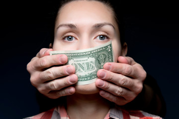 money makes a woman silent. Hands cover the mouth with a one dollar bill