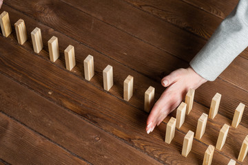 Businesswoman protecting dominoes from falling