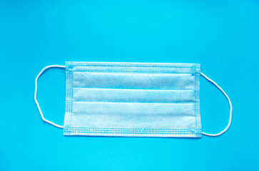 Face mask with copy space. Medical mask on blue background, top view. Hygiene and health care. Infection protection.