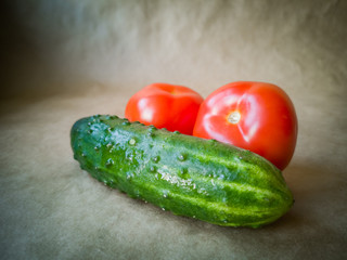 Fresh tomatoes and cucumbers on a dark background. Red tomatoes and green cucumbers close up
