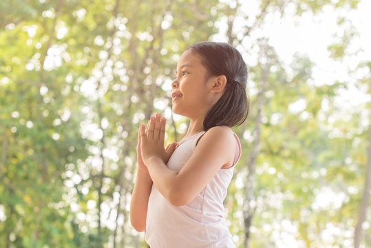 cute little girl hands praying to god with the bible in the morning on nature background.  little asian girl hand praying for thank god. copy space. spirituality and religion faith hope concept.