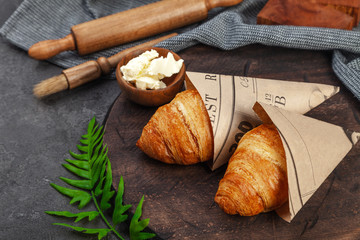 Fresh crispy baked croissants and butter on wooden board