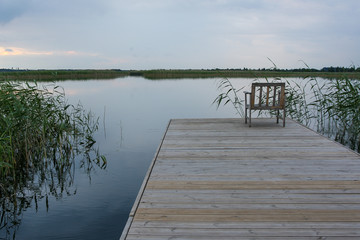 Naklejka premium A chair on a deck on a calm lake