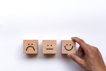 Hand of client show a feedback with smile face wood cube. Service rating, satisfaction concept