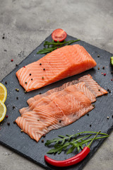 Fresh sliced salmon fillet with arugula, avocado and lemon on slate plate. Wild atlantic fish