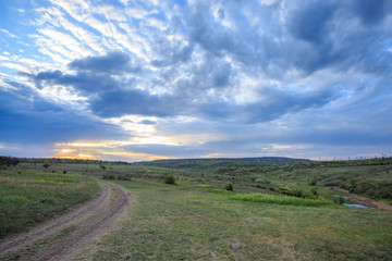 Dirt road near the river, sunset or dawn with clouds