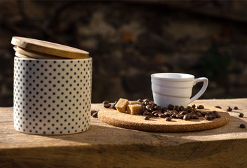 Still life with coffee cup, beans and sugar bowl in the sun