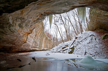 Fototapeta na wymiar Looking out from beneath a sandstone canyon overhang into a winter landscape.