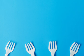  White plastic forks on a blue background. The global problem of environmental pollution. Copy space. flat lay minimalism 