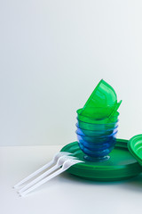 folded green plastic dishes on a white background with plastic forks