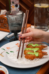 A woman is eating in a chinese restaurant. Close-up of hands and chopsticks