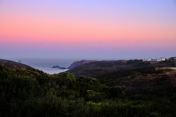 Arrifana village and Ocean in the Sunrise. Solo Backpacker Trekking on the Rota Vicentina and Fishermen's Trail in Algarve, Portugal. Walking between cliff, ocean, nature and beach.