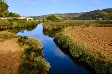 The village of Odeceixe see fron the blue river Ribeira de Seixe. Solo Backpacker Trekking on the Rota Vicentina and Fishermen's Trail in Algarve, Portugal. Walking between cliff, ocean, nature and be