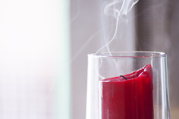 Red candle inside a clear glass vase just blown out