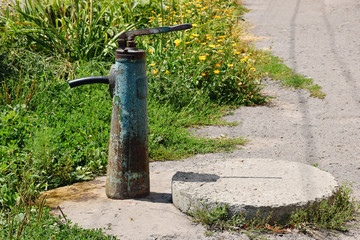 Manual steel water pump in a village street on a nice summer day, vintage style