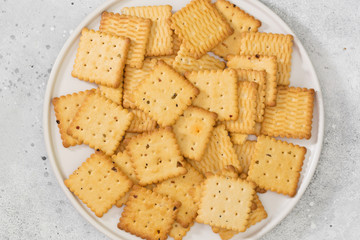 Crackers in a white plate on a light gray table. Cookie close-up with space for text. The view from the top