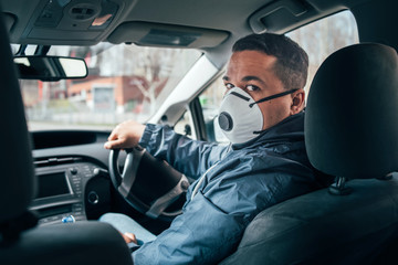 young hispanic taxi driver wearing a protective mask and talks to a client.