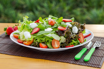 Salad with strawberry, leaves and cutlery