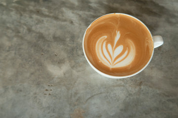 Top view of hot latte or cappuccino coffee with flower milk foam art on concrete cement counter bar at coffee shop or cafe restaurant for breakfast or lunch break time, coffeehouse concept, free space