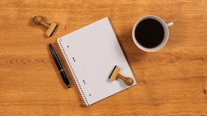 Holzschreibtisch mit Notizbuch, Kugelschreiber, Holzstempel und Kaffeetasse 