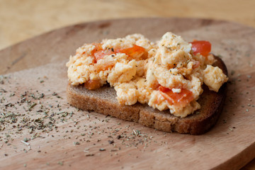 brown bread toast with scramble omelet with tomatoes and cheese. Sprinkled with oregano.