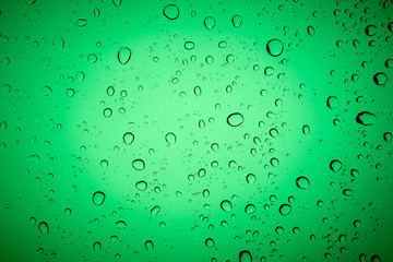 Raindrops on a green glass, abstract green background.