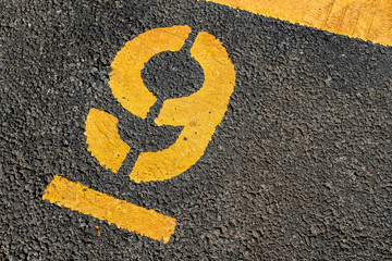 Asphalt parking lot with yellow lot line and yellow lot number 9, nine, ninth.