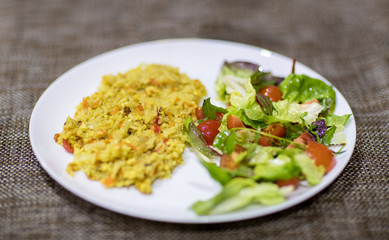 yellow rice with vegetables from tomatoes cucumbers and cabbage on white plate