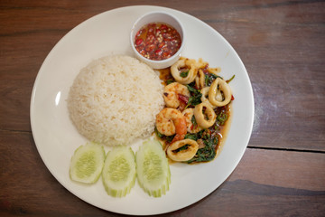 Pad Kra Pao Seafood(Thai food) - fried shrimps and squids with holy basil beside cooked rice and Chilli Fish Sauce - Stock Photo