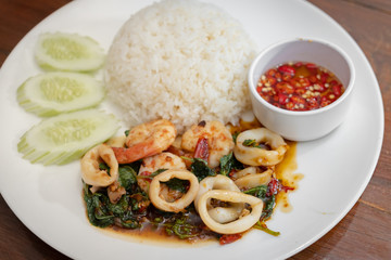 Pad Kra Pao Seafood(Thai food) - fried shrimps and squids with holy basil beside cooked rice and Chilli Fish Sauce - Stock Photo