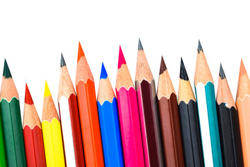 Different colored wooden pencil crayons placed in a row in front of a white background