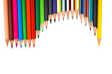 Different colored wooden pencil crayons placed in a wave shaped row in front of a white background