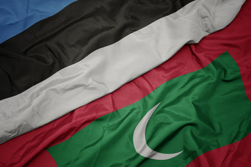 waving colorful flag of maldives and national flag of estonia.