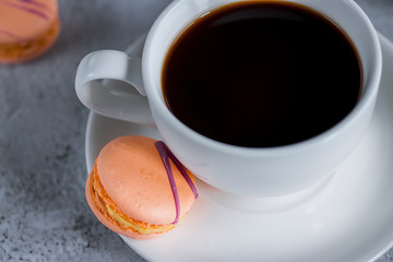 White cup espresso and bright macaroon cakes on concrete background. Close-up.