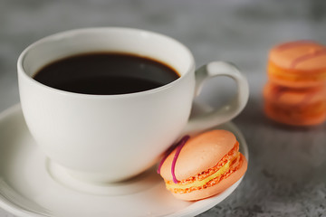 White cup espresso and bright macaroon cakes on concrete background. Close-up.