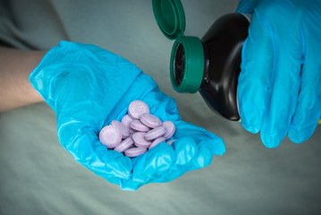 Fototapeta premium Hands wearing surgical gloves and holding medication bottle and vitamin C tablets