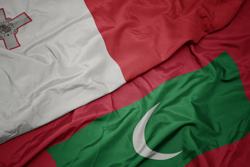 waving colorful flag of maldives and national flag of malta.