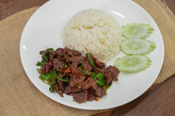 Pad Kra Pao Beef - Stir fried beef with holy basil on Sack cloth above the wooden table - Horizontal