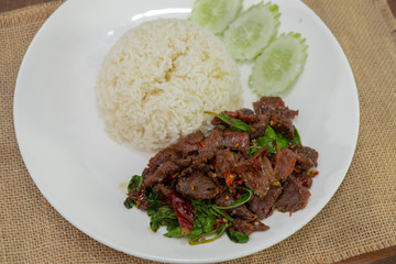 Pad Kra Pao Beef - Stir fried beef with holy basil on Sack cloth above the wooden table - Horizontal