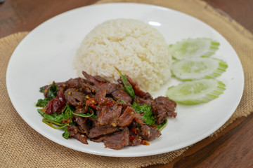 Pad Kra Pao Beef - Stir fried beef with holy basil on Sack cloth above the wooden table - Horizontal